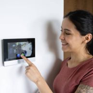 istockphoto-1389740839-612×612 Latin American woman at home using the intercom to talk to a delivery person - lifestyle concepts. **DESIGN ON SCREEN WAS MADE FROM SCRATCH BY US**