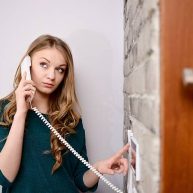 istockphoto-506473178-612×612 Young blonde woman talking on the intercom and presses the button to open the door